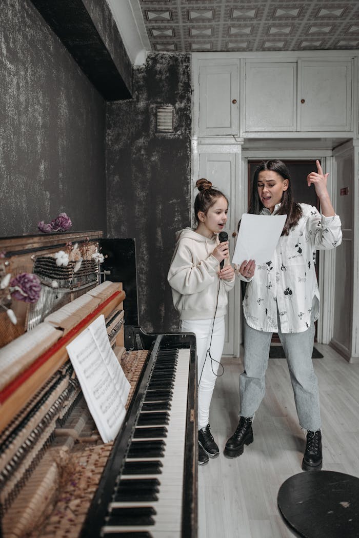 Two women engaged in a music lesson with piano and microphone in a studio.